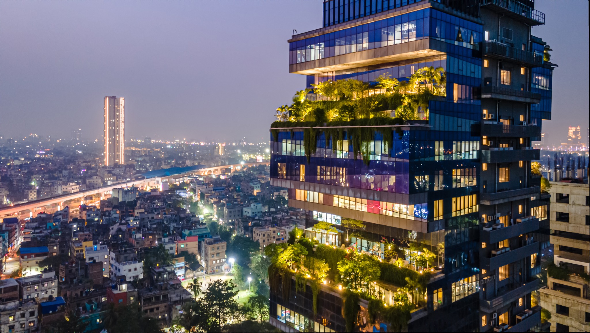 Illuminated planted terraces on the Biowonder tower above Kolkata at dusk