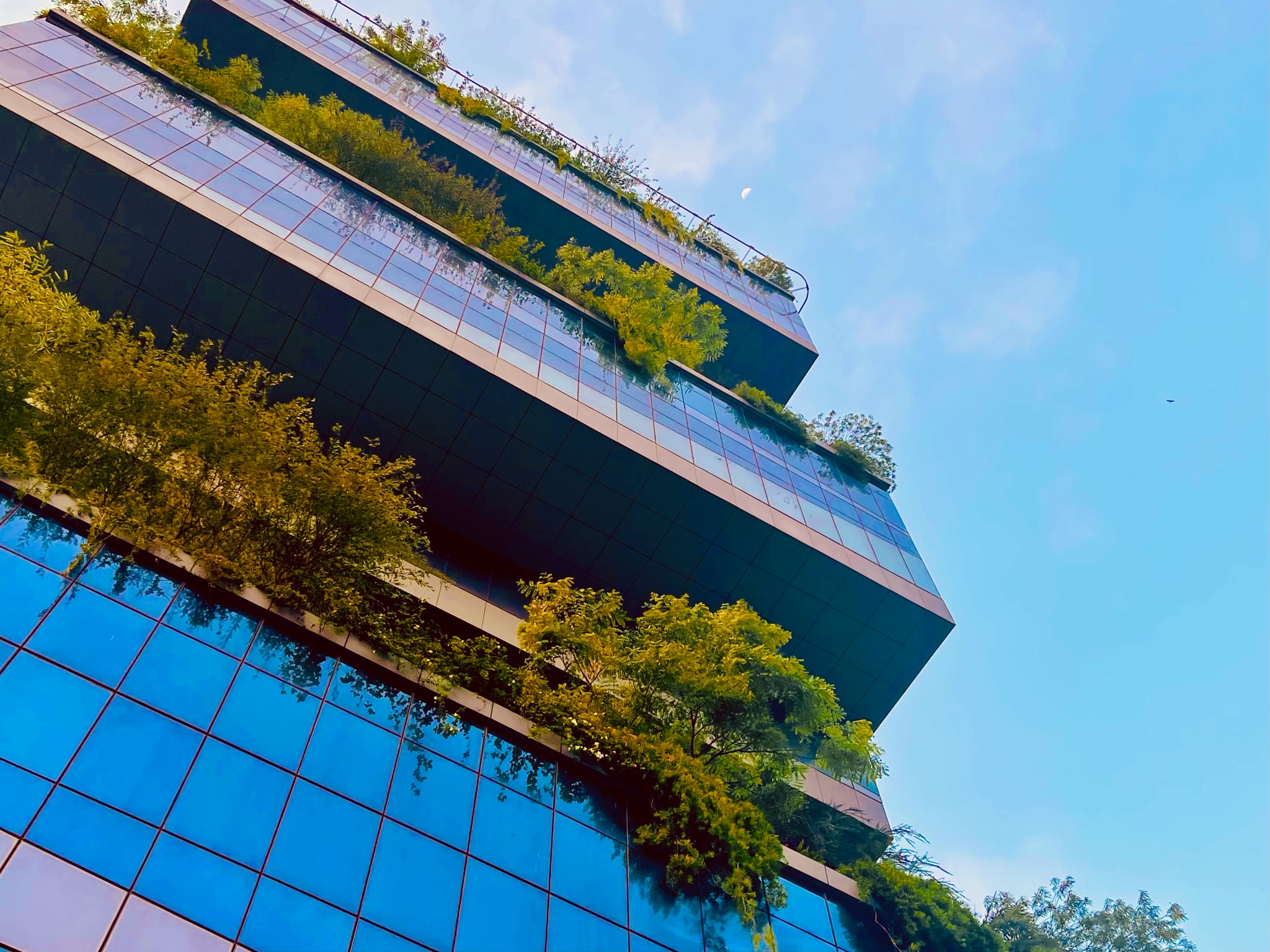 Low-angle view of cantilevered terraces and cascading planting on Biowonder’s glass facade, Kolkata